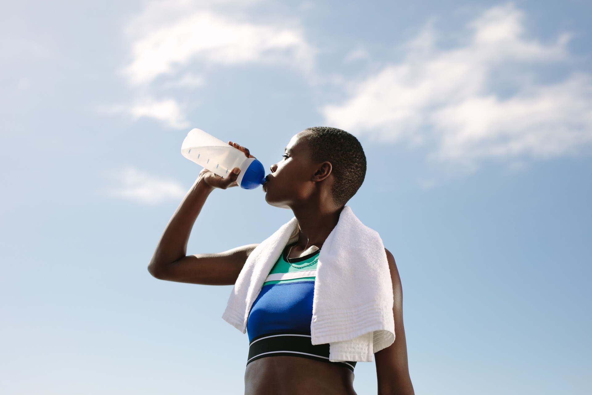 Fitness woman drinking water against sky