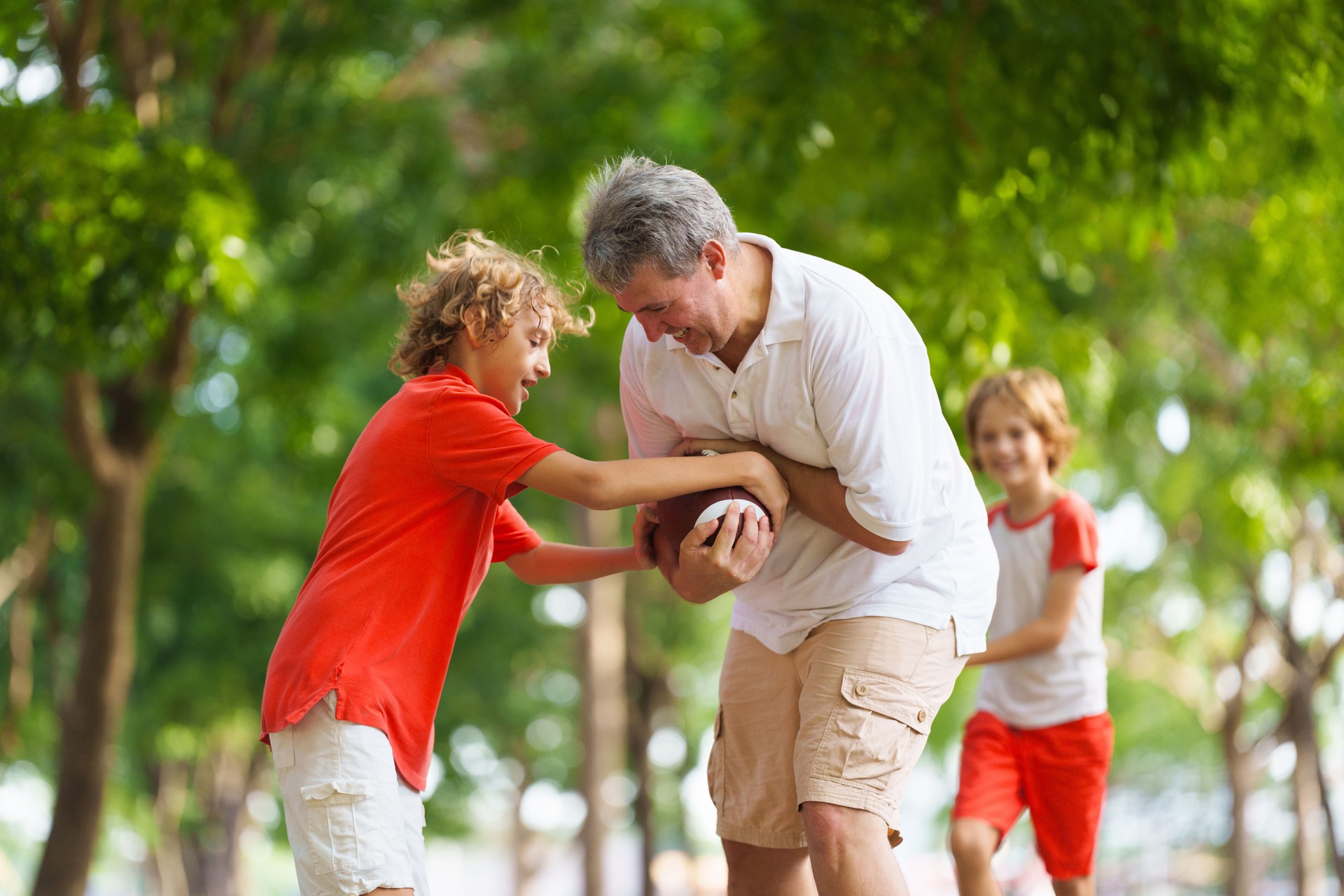 Family playing American football. Kids play rugby